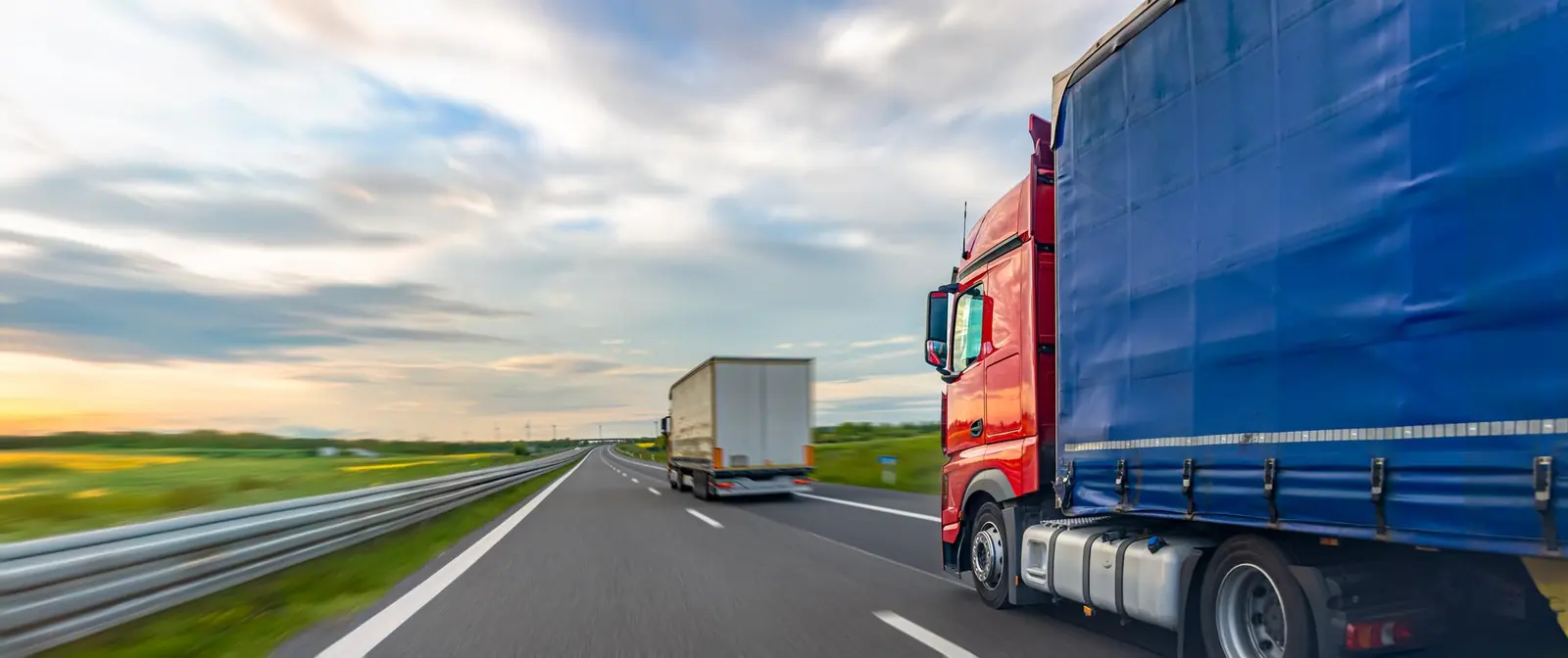 Tractocamión rojo con carpa azul en autopista